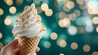 Soft serve vanilla ice cream cone with golden sprinkles against blurred turquoise and gold bokeh background creates festive mood for dessert and celebration designs.