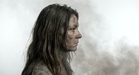 Primitive woman with long dark hair in profile against smoky background, depicting early human evolution and prehistoric lifestyle concepts.