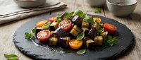 Fresh roasted beet salad with cherry tomatoes, herbs and olive oil on dark slate plate. Healthy vegetarian Mediterranean cuisine for restaurant menu design.