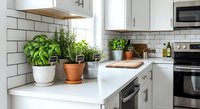 Modern kitchen counter with fresh herbs in pots including basil and rosemary on white countertop. Clean contemporary design with subway tile backsplash.