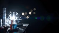 Laboratory glassware with colorful chemical solutions on dark background with bokeh lights for scientific research and experimentation concepts.