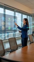 Professional businesswoman interacting with futuristic holographic interface displaying data analytics and AI technology in modern corporate boardroom.