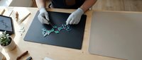Professional technician repairing smartphone motherboard with precision tools on anti-static mat in modern electronics repair workshop environment.