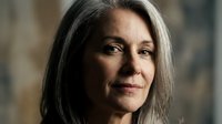 Middle-aged woman with long gray hair and fair complexion, displaying a gentle, contemplative expression. Suitable for healthcare, wellness, aging gracefully, and lifestyle editorial use.