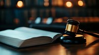 Wooden gavel and open law book on desk with warm lighting creating professional legal atmosphere for attorney office or courtroom setting.