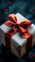 White gift box wrapped with elegant coral red satin ribbon bow against dark moody background with pine branches and red berries, festive holiday concept.