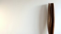Modern tall brown wooden vase with curved design against white wall, contemporary home decor accent piece for minimalist interior styling.