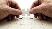 Elderly hands placing final puzzle piece to complete jigsaw puzzle, symbolizing problem solving, teamwork and achievement in business strategy.