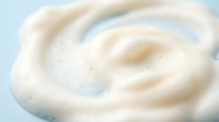 White creamy swirl texture with smooth flowing curves and soft highlights creating elegant abstract pattern for cosmetic and skincare product backgrounds.