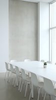 Minimalist conference room with white table, modern chairs, and concrete accent wall beside large windows for corporate meetings and business presentations.
