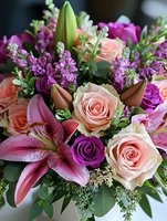 Romantic floral arrangement with pink lilies, peach roses, purple stock flowers and greenery creates elegant bouquet for weddings, celebrations and special occasions.