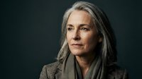 Professional mature woman with gray hair in business attire against dark background for corporate headshot and executive portrait photography.