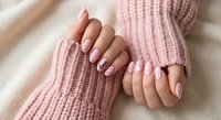 Female hands with pink manicure and nail art in cozy pink knit sweater sleeves. Soft feminine style for beauty and fashion content.