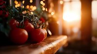 Fresh ripe red tomatoes on wooden surface with water drops and warm bokeh lights in background creating cozy kitchen atmosphere.