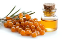 Fresh sea buckthorn berries and organic oil in glass bottle with cork stopper on white background, natural vitamin supplement and superfood concept.