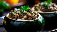 Stuffed round zucchini with seasoned ground meat, herbs and spices served as appetizer. Dark green squash filled with savory mixture garnished with fresh parsley.