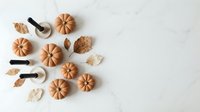 Autumn pumpkin cookies with spices and leaves on white marble background, perfect for fall baking and seasonal dessert projects.