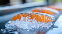 Fresh salmon fillets on crushed ice in metal tray, raw fish seafood preparation for cooking, restaurant kitchen food ingredients ready for culinary use.