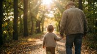Grandfather and grandson walking hand in hand on forest path during golden hour sunset. Warm family bonding moment in autumn woodland setting.