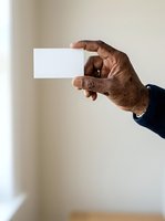 Senior male hand holding blank white business card against neutral background. Ideal for corporate identity, contact information, and professional networking concepts.
