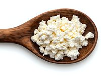 Fresh cottage cheese in wooden spoon isolated on white background. Natural dairy product with grainy texture for healthy eating and cooking.