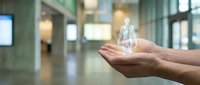 Hands holding glowing human hologram in modern office space representing digital healthcare technology and medical innovation for business presentations.