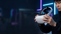 Young Asian male wearing black clothing holding white virtual reality headset in neon-lit environment for gaming, entertainment, and technology concepts.