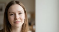 Young Caucasian woman with long brown hair smiling warmly at camera in bright indoor setting for lifestyle and portrait photography projects.