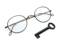 Vintage round eyeglasses with metal frames and antique key isolated on white background, ready for design projects, clipart, and merchandise applications.