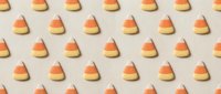 Candy corn pattern on beige background creates festive Halloween decoration for autumn celebrations and seasonal designs.