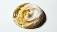 Swirled cream and golden liquid blend together in smooth, flowing motion against white background, isolated for design use.