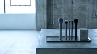 Modern minimalist kitchen utensil holder with black tools on concrete counter in contemporary industrial interior design setting.
