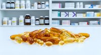 Omega-3 fish oil capsules and vitamin supplements scattered on pharmacy counter with medicine bottles on shelves in background for health concept.