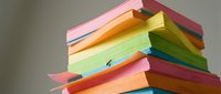 Colorful stacked books with vibrant rainbow pages fanned out, isolated on white background, ready for education and learning design projects.