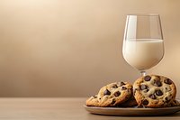 Fresh baked chocolate chip cookies on ceramic plate with glass of milk against warm beige background, classic comfort food styling for dessert menus.