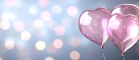 Pink heart shaped balloons floating against soft bokeh background in pastel blue and pink tones, romantic celebration atmosphere for Valentine's day or wedding design.