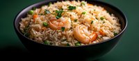 Aromatic shrimp fried rice garnished with fresh herbs in black bowl against dark background, selective focus on juicy seafood and fluffy grains.