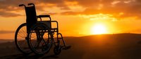 Silhouette of empty wheelchair against golden sunset sky with mountains in background, symbolizing hope, recovery, rehabilitation, and overcoming physical challenges.