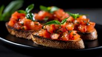 Fresh tomato bruschetta with basil and herbs on toasted bread slices against dark background, close up view of traditional Italian appetizer garnished with herbs.