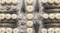 Autumn flat lay with white pumpkins, dried lavender bundles and amethyst crystals arranged in symmetrical pattern on neutral background for seasonal decor.