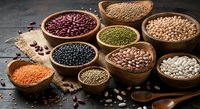 Assorted legumes and beans in wooden bowls on rustic table. Variety of lentils, chickpeas, kidney beans for healthy cooking and nutrition concepts.