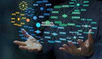 Business professional hands presenting knowledge management network diagram with interconnected concepts and technology nodes on dark background.