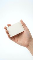 Hand holding blank white business card mockup on light background for branding and corporate identity design projects.