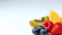 Fresh mixed fruits including strawberry, blueberries, kiwi slice and orange segment arranged on white background for healthy eating and nutrition concepts.