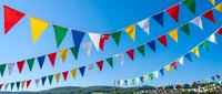 Colorful triangular bunting flags hanging against bright blue sky creating festive party atmosphere for celebrations and outdoor events.
