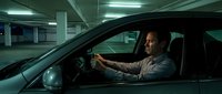 Middle-aged Caucasian businessman driving luxury car in underground parking garage at night with atmospheric lighting and urban professional lifestyle.