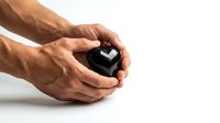 Male hands gently holding black geometric cube object on white background, isolated for design use in business concepts and presentations.
