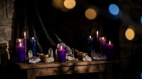 Mystical altar setup with purple candles, crystals, and ritual items on wooden table with warm bokeh lights creating magical atmosphere for spiritual practices.
