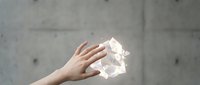 Hand holding glowing geometric crystal structure against concrete wall background for modern technology and innovation concepts.