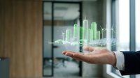 Businessman hand holding holographic cityscape with green buildings and wind turbines for sustainable urban development and renewable energy planning.